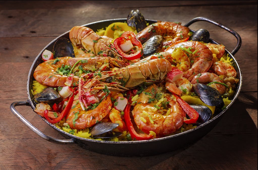 A vibrant and flavorful seafood paella served in a pan with mussels and shrimp.
